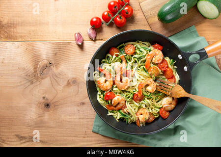 Spaghetti de courgettes sautées à la tomate cerise et de crevettes dans une casserole sur une table en bois rustique. Vue d'en haut Banque D'Images