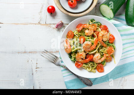 Nouilles sautées aux courgettes et tomates cerise et de langoustines dans un plat sur une table en bois blanc rustique. Vue d'en haut Banque D'Images