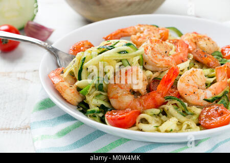 Nouilles sautées aux courgettes et tomates cerise et de langoustines dans un plat sur une table en bois blanc rustique. Close up Banque D'Images