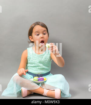 Petite fille excité avec une assiette pleine de macarons Banque D'Images