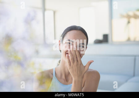 Laughing brunette woman couvrant la bouche Banque D'Images