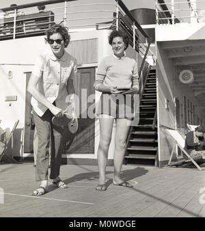 Années 1950, historiques, deux jeunes femmes à bord d'un château-Union Steamship jouant un jeu de carte de quoits ou similaires impliquant les disques ronds de jeter avec les trous de. Banque D'Images