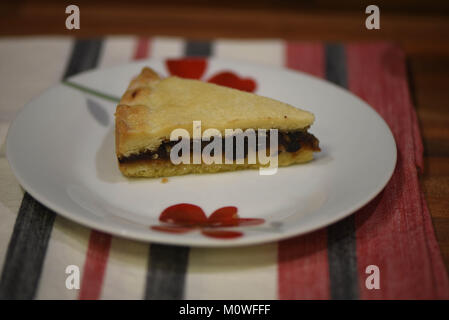 La photographie culinaire avec pâtisseries et fruits en cours de coupe sur une tarte Eccles anglaise rouge et blanc avec la plaque de fond en tissu de table Banque D'Images