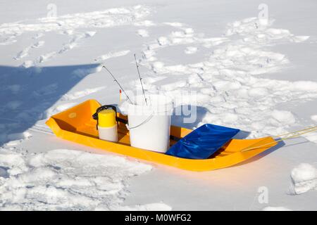 Un traîneau jaune avec des engins de pêche sur la glace d'un lac du Minnesota. Banque D'Images