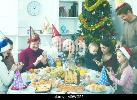 Les membres de la famille heureuse à la recherche à travers des photos au cours d'un dîner de Noël Banque D'Images