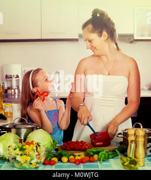 Petite fille avec maman couper des légumes pour la soupe à la cuisine Banque D'Images