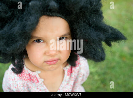 Portrait de petite fille portant une grande perruque noire Banque D'Images