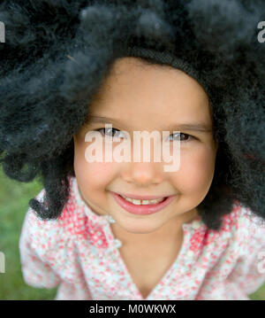 Portrait de petite fille portant une perruque big black and smiling Banque D'Images