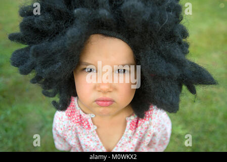 Portrait de petite fille portant une grande perruque noire Banque D'Images