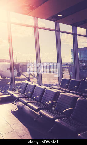 Des sièges vides dans le hall de départ d'un aéroport au coucher du soleil, la couleur tonique Voyages et transport concept photo avec effet lens flare. Banque D'Images