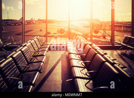 Des sièges vides dans un aéroport hall de départ au coucher du soleil, aux teintes de couleur photo, voyages et transport concept. Banque D'Images