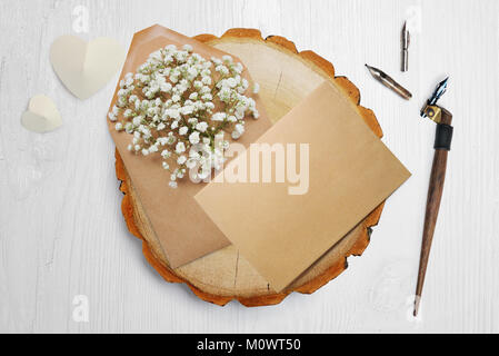 Plume calligraphique, se trouve à proximité d'un cercle en bois avec un papier blanc coeur. carte de souhaits pour la Saint-Valentin avec place pour votre texte. Mise à plat, haut voir photo maquette Banque D'Images