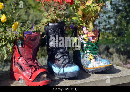 Vieux Bottes colorés recyclés dans les semoirs à jusqu'à un mur à RHS Garden Harlow Carr,, Harrogate, Yorkshire. UK. Banque D'Images