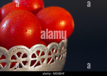 Tomates mûres rouges avec des gouttes d'eau dans un bol en métal sur fond noir libre Banque D'Images