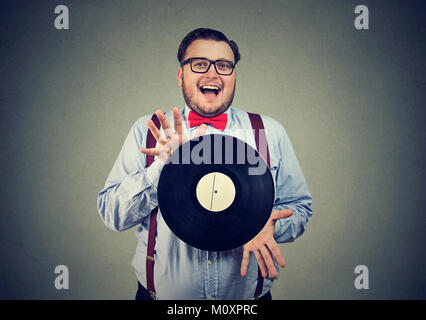 Chubby homme heureux en bow-tie heureux avec disque vinyle obsédé par la musique. Banque D'Images