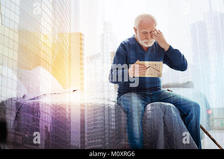 Vieille personne de pleurer en regardant la photo dans ses mains Banque D'Images