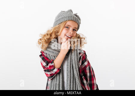 Portrait of a smiling little girl dressed in winter hat and scarf looking at camera isolated over white background Banque D'Images