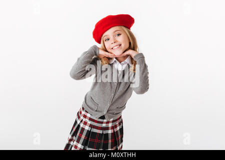 Portrait of a smiling little schoolgirl habillés en uniforme posing and looking at camera isolated over white background Banque D'Images