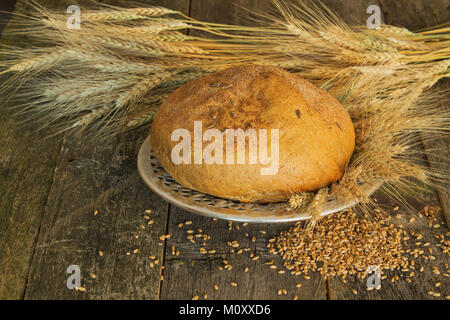 Du pain sur une vieille plaque de métal avec des oreilles et des grains de blé sur le fond en bois Banque D'Images