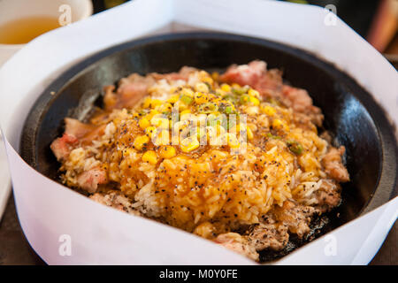 Steak au poivre Teppanyaki grésillant avec déjeuner garni de riz et maïs sucré Oignons verts sur une plaque de fer électromagnétique. Un morceau de papier blanc surrou Banque D'Images