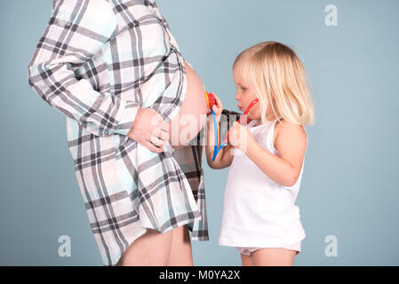 Little girl holding stethescope jusqu'aux mamans pregnant belly Banque D'Images
