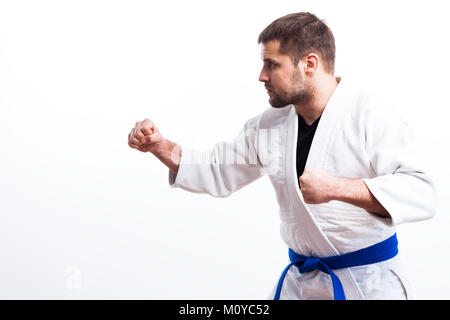 Jeune homme fighter dans un kimono blanc avec ceinture noire pour le judo, le jiu-jitsu posent sur fond blanc isolé Banque D'Images