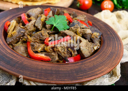 Salade chaude de foie et le poivron dans une cuvette d'argile sur une table en bois sombre. Poêlée de foie. Banque D'Images