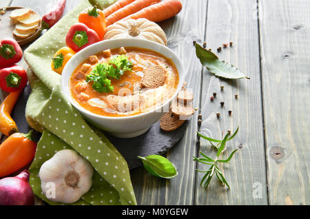 Soupe de légumes épicé au four avec poivrons, tomates, carottes, piments, l'oignon rouge, l'ail et le gingembre dans un bol en céramique sur la table en bois. La soupe est Banque D'Images