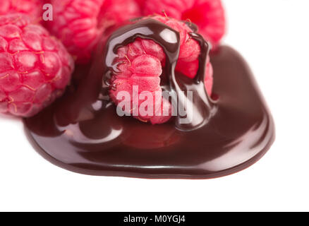 Framboises fraîches dans la sauce au chocolat isolé sur blanc, composition d'angle Banque D'Images