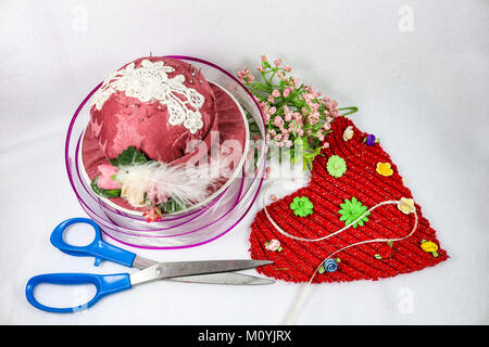 La couture et l'artisanat pour Saint Valentin - Pink hat pin cushion et sissors avec du ruban et des fleurs et un coeur en tissu rouge Banque D'Images