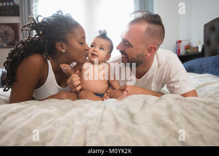 Mère et père portant sur le lit avec bébé fille Banque D'Images
