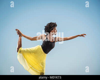 Femme Noir debout sur une jambe pied holding Banque D'Images