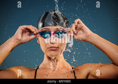 Les éclaboussures d'eau sur Caucasian woman réglage de lunettes de natation Banque D'Images