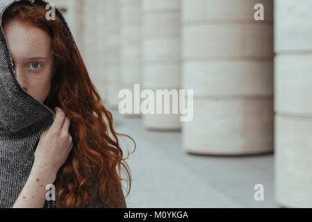 Caucasian woman se cachant derrière hood Banque D'Images