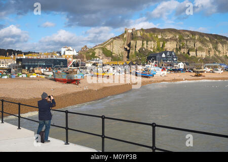 Près de la vieille ville de Hastings plage des pêcheurs ; un photographe saisit la scène pittoresque de mouettes tournoyant autour des bateaux de pêche, East Sussex, UK Banque D'Images