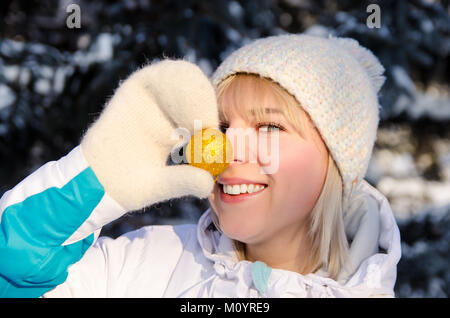 Belle blonde smiling girl in sportswear s'amuse, mettre son nez à un bal de Noël jaune représentant un clown outdoor Banque D'Images