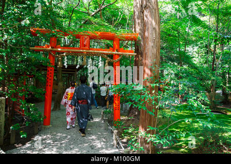 Couple japonais en kimono rouge marche à travers le torii à la forêt de Arashiyama, à Kyoto, Japon Banque D'Images