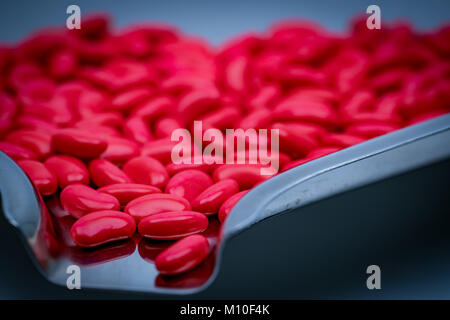 Détail d'un plan macro forme de rein rouge comprimés enrobés de sucre sur le plateau de la drogue en acier inoxydable Banque D'Images