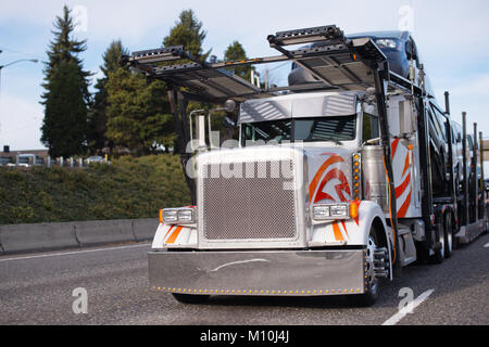 Classic big rig semi truck avec grille carrée de deux étages et d'une voiture compacte du commissionnaire de transport semi-remorque en marche sur la route de décharger le transport des marchandises Banque D'Images