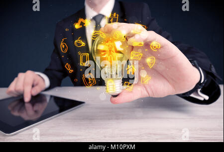 Un bureau commercial promouvoir ses idées de concept avec l'illustration des médias en ligne et les logos de l'appareil autour de l'ampoule en verre électrique. Banque D'Images