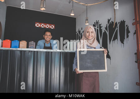 Heureux propriétaire de petite entreprise prêt à ouvrir son café pour la première fois. holding white board Banque D'Images