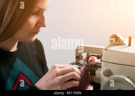 Une jeune femme scinner, fourreur coud un manteau de fourrure lumineux bleu naturel de fourrure sur machine à coudre Banque D'Images