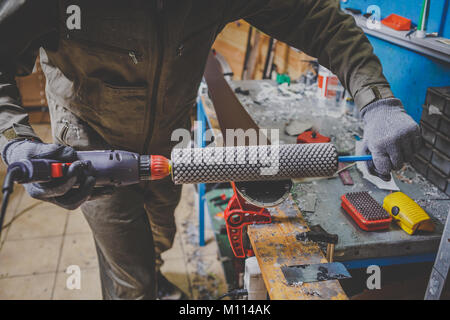 Un homme en vêtements de travail un réparateur à un atelier ski service ski une surface de glissement, polissage, Base de ski finale le polissage. Dans les mains d'une brosse électrique Banque D'Images