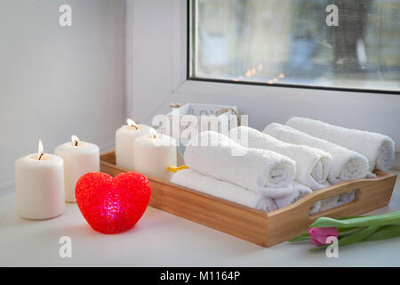 Serviettes roulées sur un plateau à côté des chandelles et un bouquet de tulipes dans la spa salon Banque D'Images