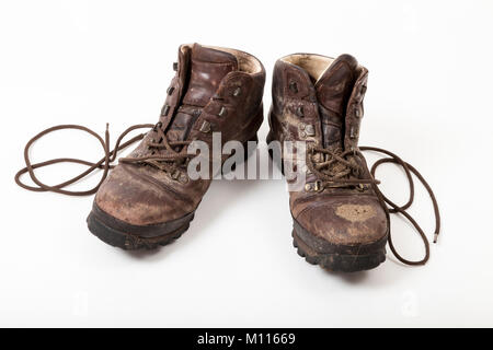 Une vieille paire de bottes de randonnée en cuir boueux sur fond blanc Banque D'Images