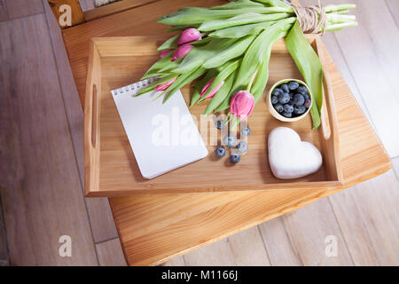 Un plateau avec thé et d'épices en forme de cœur et un bouquet de tulipes sur la chaise Banque D'Images