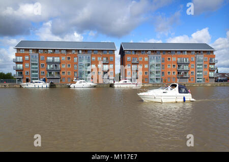 Nouveaux immeubles du développement à Gloucester Docks, Gloucester, Royaume-Uni Gloucester, Royaume-Uni - 24 août 2010 : un petit bateau quitte le port de plaisance en face d'un nouvel immeuble du développement à Gloucester Docks, Gloucester, Royaume-Uni. Construit en 2004-2005, ces appartements ont été la première promotion dans le récent réaménagement du site des quais historiques. Banque D'Images