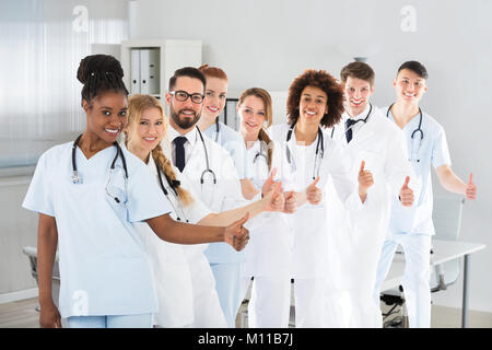 Groupe de médecins masculins et féminins ethniques Showing Thumb Up Sign In Clinic Banque D'Images