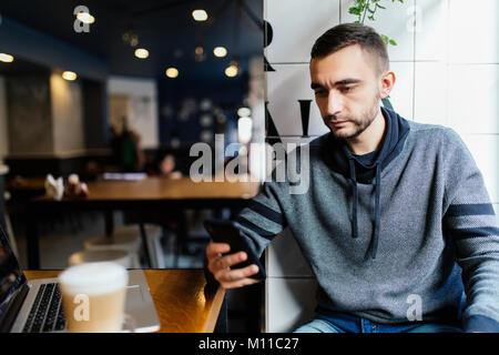 Close-up of male hands holding et à l'utilisation de smart phone in cafe shop. L'envoi de l'homme moderne les nouveaux messages sur téléphone intelligent. Banque D'Images