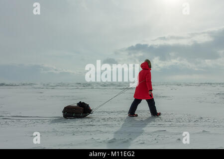 Femme avec un traîneau à pied est sur la glace du lac Baïkal. Banque D'Images